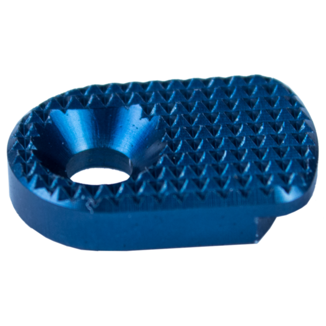 Close-up of the MAGAZINE CATCH PADDLE SHADOW 2 BLUE, a textured metal component with an oval shape and a central conical indentation. The surface is adorned with a diamond-patterned texture, while the edges are smooth.