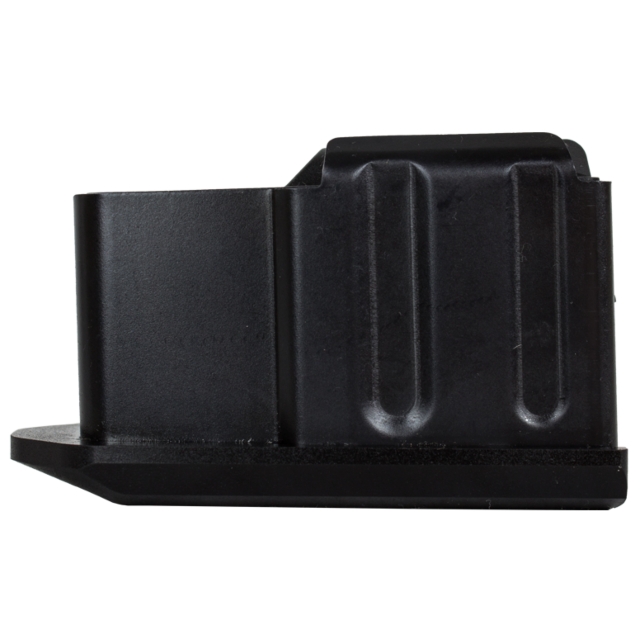 The object, viewed from its side, resembles a black metallic box with ridged sides and a rectangular shape. It appears similar to the MAG CZ 557 .243/.308/6.5 CREEDMOOR 4 RD magazine, featuring a broad base and a small indentation on the left side.