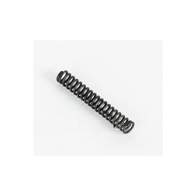 A compact, coiled metal spring named SLIDE STOP SPRING BREN 2 rests diagonally on a plain white surface, with one end slightly elevated. It exhibits a black appearance, tightly wound with a subtle shadow cast beneath it.