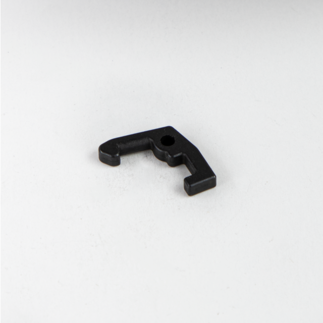 A small COCKING LEVER LATCH BREN 2, featuring a black metallic finish and an L-shaped design with a hole in the center, is placed on a plain white surface.